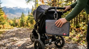 Illustration of a portable changing pad for travel clipped to a jogging stroller on a Canadian mountain trail.