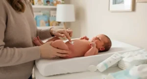 Parent gently applying soothing diaper rash cream for newborns during a diaper change.